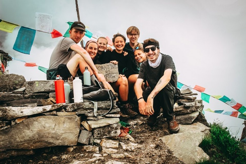 Friends sitting on a hilltop with Buddhist prayer flags behind them